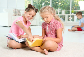 Cute little girls reading books at home