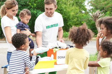 Volunteers sharing clothes and toys with poor African children outdoors