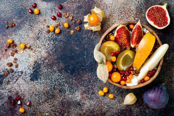 Fototapeta na wymiar Fall breakfast bowl with chocolate granola, coconut yogurt and autumn seasonal fruits and berries. Healthy vegan, vegetarian breakfast table