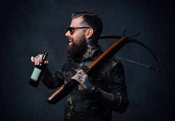 Fototapeta na wymiar A man holds the craft beer bottle and a crossbow.