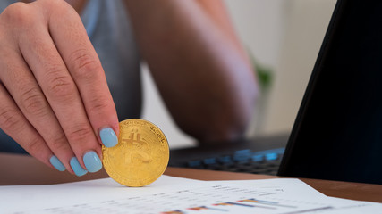 Young woman holding golden bitcoin in office