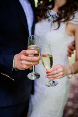 Happy wedding couple poses with champagne flutes in the park