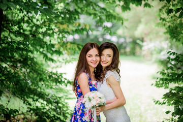 Naklejka premium Bride and bridesmaid hug standing in the park