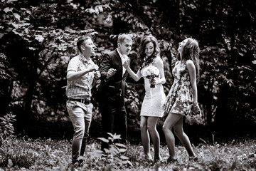 Black and white picture of newlyweds and their friends dancing in the park