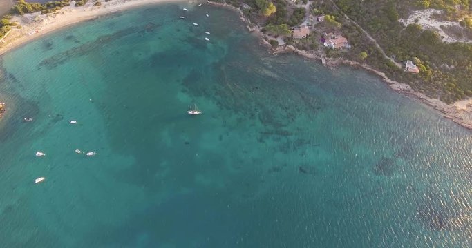 Aerial, beautiful bay in Sardinia island and few ancored yachts on sunset, 4K