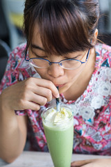 Asian girl drinking iced matcha green tea with straw