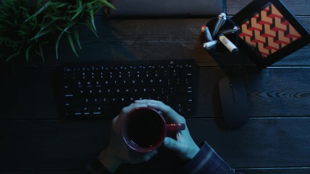 Overhead view of man drinking coffee while sitting in front of computer