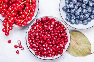 Purple and red color fruits in bowls top view.Berries, pomegranate, redcurrant winter fruits healthy snack.