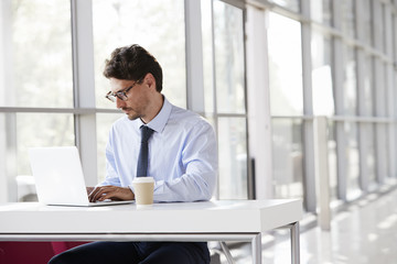 Fototapeta premium Young businessman at a desk working on his laptop