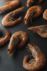 Shrimps on black background. Delicious seafood appetizer served boiled or grilled with spices. Close up. Top view