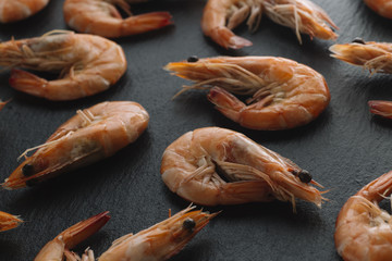 Shrimps on black background. Delicious seafood appetizer served boiled or grilled with spices....