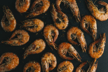 Shrimps on black background. Delicious seafood appetizer served boiled or grilled with spices. Close up. Top view