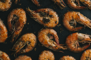 Shrimps on black background. Delicious seafood appetizer served boiled or grilled with spices. Close up. Top view