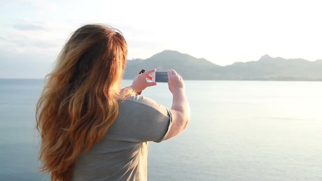 woman with long hair makes a photo on the phone