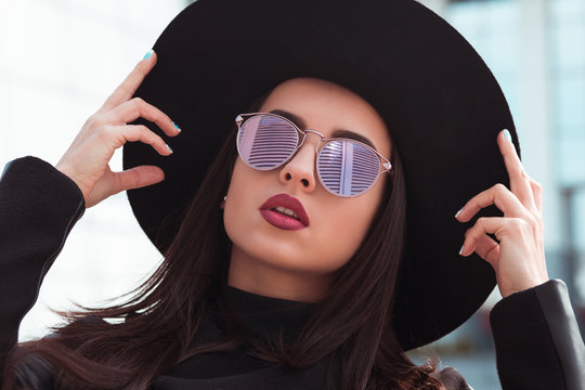 Street portrait of fashionable model in trendy sunglasses and stylish hat. Female fashion concept