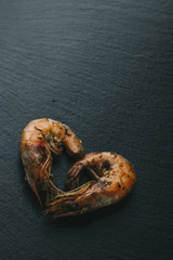Shrimps on black background. Delicious seafood appetizer served boiled or grilled with spices. Close up. Top view