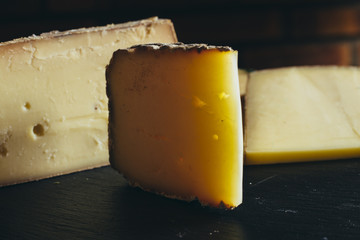 Cheese assortment on black background. Various sorts of cheese for appetizing, gourmet, delicious snacks. Traditional French dish served with wine for lunch and dinner. Closeup. Toned