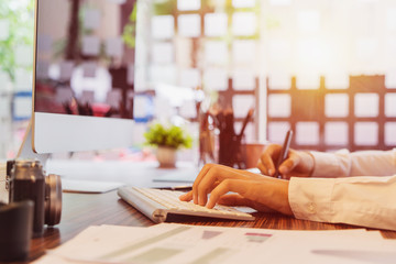 Young asian female designer using graphics tablet while working with computer at studio or office.	