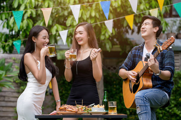 Asian young man are playing guitar with girls at the outdoor party.