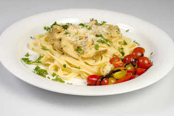 Fresh handmade tagliatelle pasta with forest mushrooms, parsley and cherry tomatoes salad on white