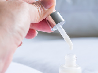 Closeup of hand and serum drop. Skin care or beauty background.