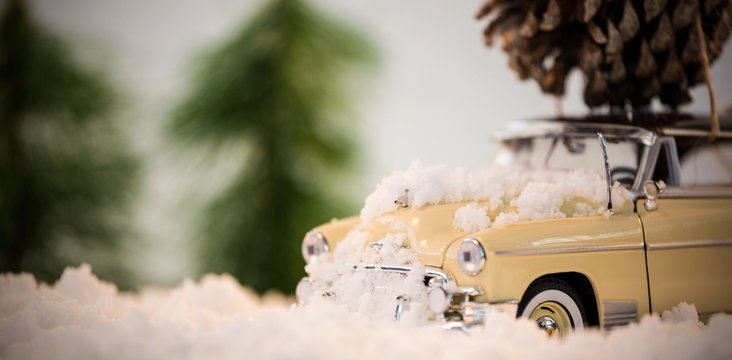 Toy car carrying pine cone on fake snow - Powered by Adobe