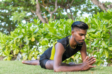 Naklejka na ściany i meble Young yoga man practitioners doing yoga on nature. Asian indian yogis man on the grass in the park. Bali island.