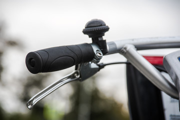 Bicycle handlebar, brake lever and bel close-up over blurred avenue