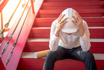 Engineer or Architect feeling tired and headache with his job. sitting on building stairs with...