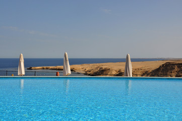 View of the blue red sea, through the blue pool with umbrellas