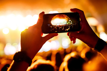 Fan taking photo of concert at festival by smatphone