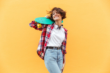 Cheerful young teenage girl holding skateboard on her shoulders © Drobot Dean