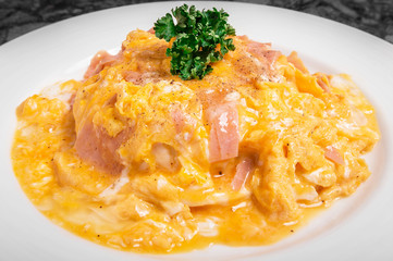 Omelet with ham on rice in white dish.