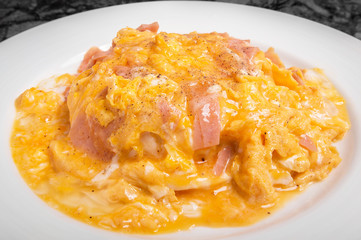 Omelet with ham on rice in white dish.