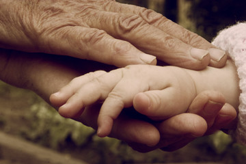 Baby hands in old wrinkled hands grandmother close-up