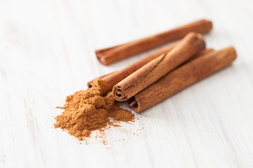 Cinnamon sticks and ground cinnamon on a white wooden table