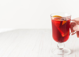 A glass of mulled wine on white wooden table