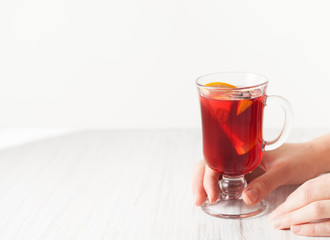 A glass of mulled wine in hand on a white table