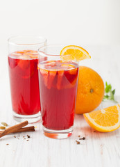 Mulled wine in glass cups with orange slices on a white table