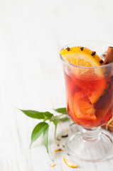 Part of a glass of mulled wine with slice of orange stuck with cloves