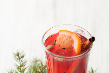 Part of a glass of mulled wine with slice of orange and cinnamon