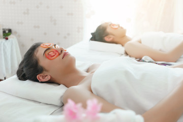 Fototapeta na wymiar Beautiful young Asian women relaxing , lying on massage table and having fresh sliced tomatoes mask for spa treatment