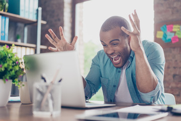 Going crazy at work. Young entrepreneur is shocked of the fail he has in business, he is yelling...