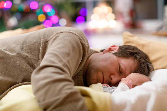 Middle Aged Father Sleeping Near His Newborn Baby Daughter On Christmas