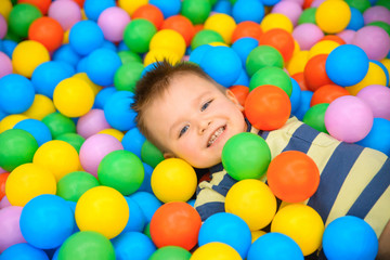 Fototapeta na wymiar A boy in the playing room with many little colored balls
