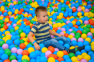 Fototapeta na wymiar A boy in the playing room with many little colored balls