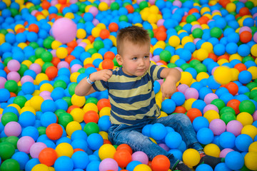 A boy in the playing room with many little colored balls