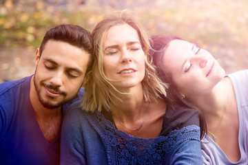 Fototapeta premium portrait of three friends sitting outside in the sun