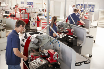 Trainee engineers operating equipment in a small factory