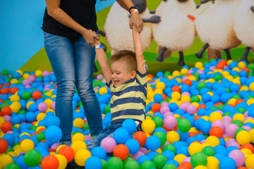 A boy with mother in the playing room with many little colored balls